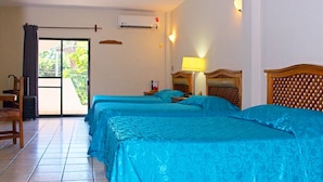 A hotel room with two beds, a chair, a table, and a view of the outdoors. - Hotel Las Fuentes (Los Mochis)