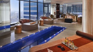 A modern hotel lobby with a large indoor pool, comfortable seating areas, and a city view. - The H Dubai (Dubai)