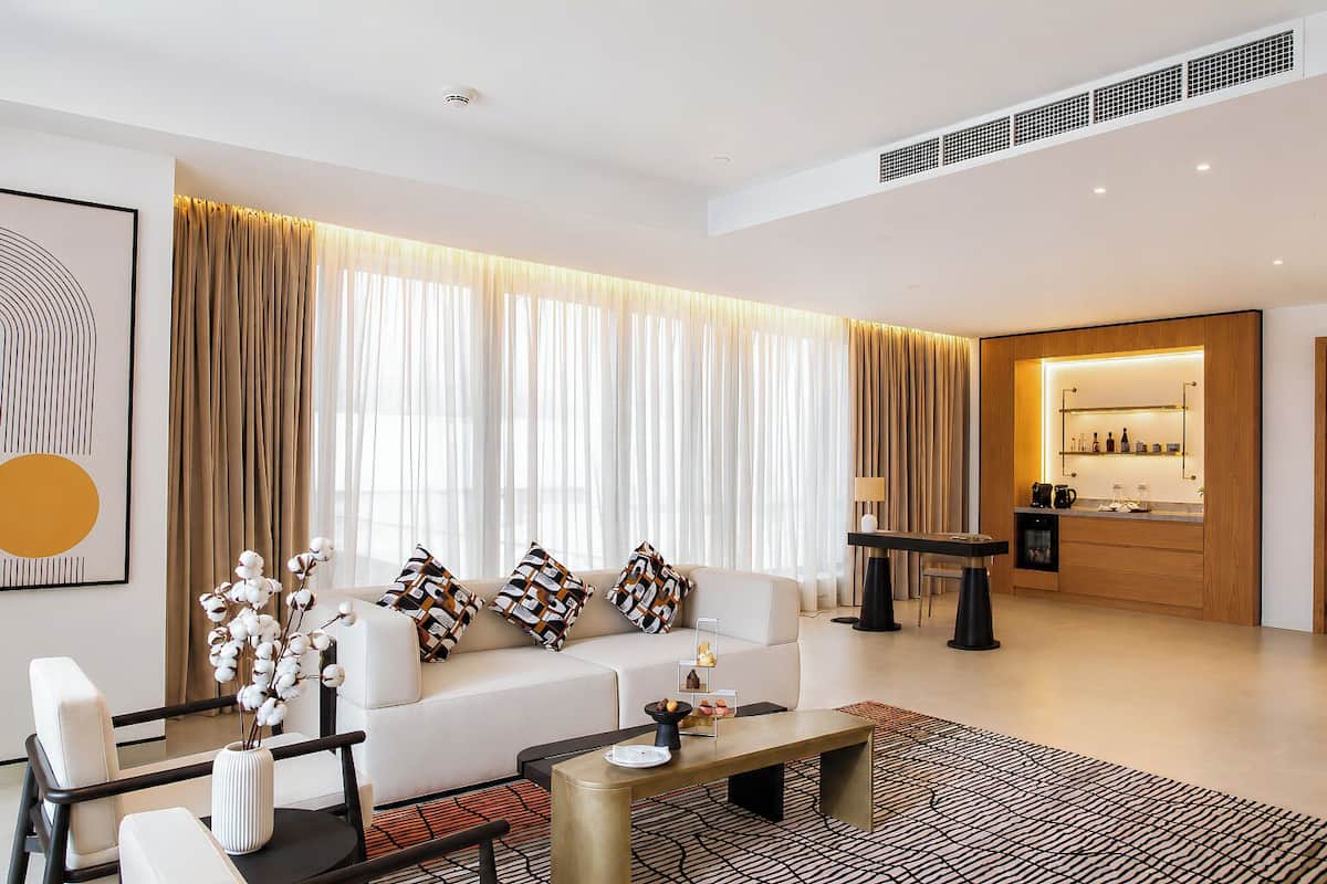 A modern living room with a sofa, coffee table, and a dining area with a table and chairs.