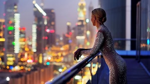 A person in a sparkly outfit standing by a railing with a cityscape in the background. - The H Dubai (Dubai)