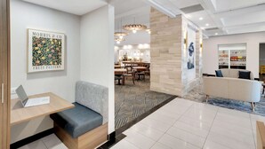 A modern hotel lobby with a seating area, a dining area, and a reception desk. - Homewood Suites by Hilton Toronto-Markham (Markham)
