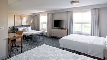 A hotel room with a bed, a desk, a chair, a TV, and a window with curtains.