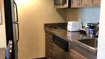 A compact kitchen with a refrigerator, microwave, dishwasher, and a sink.
