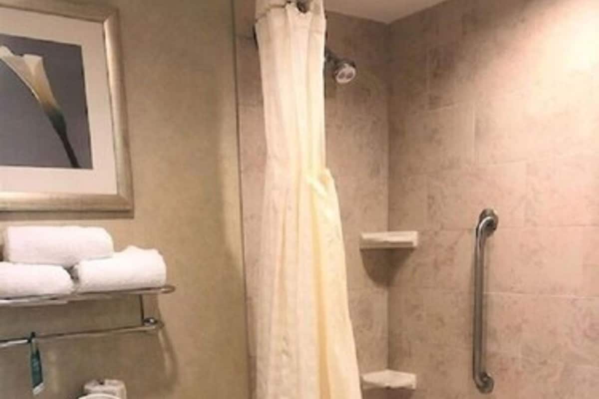 A bathroom with a toilet, a bathtub, a shower curtain, and a towel rack with towels.