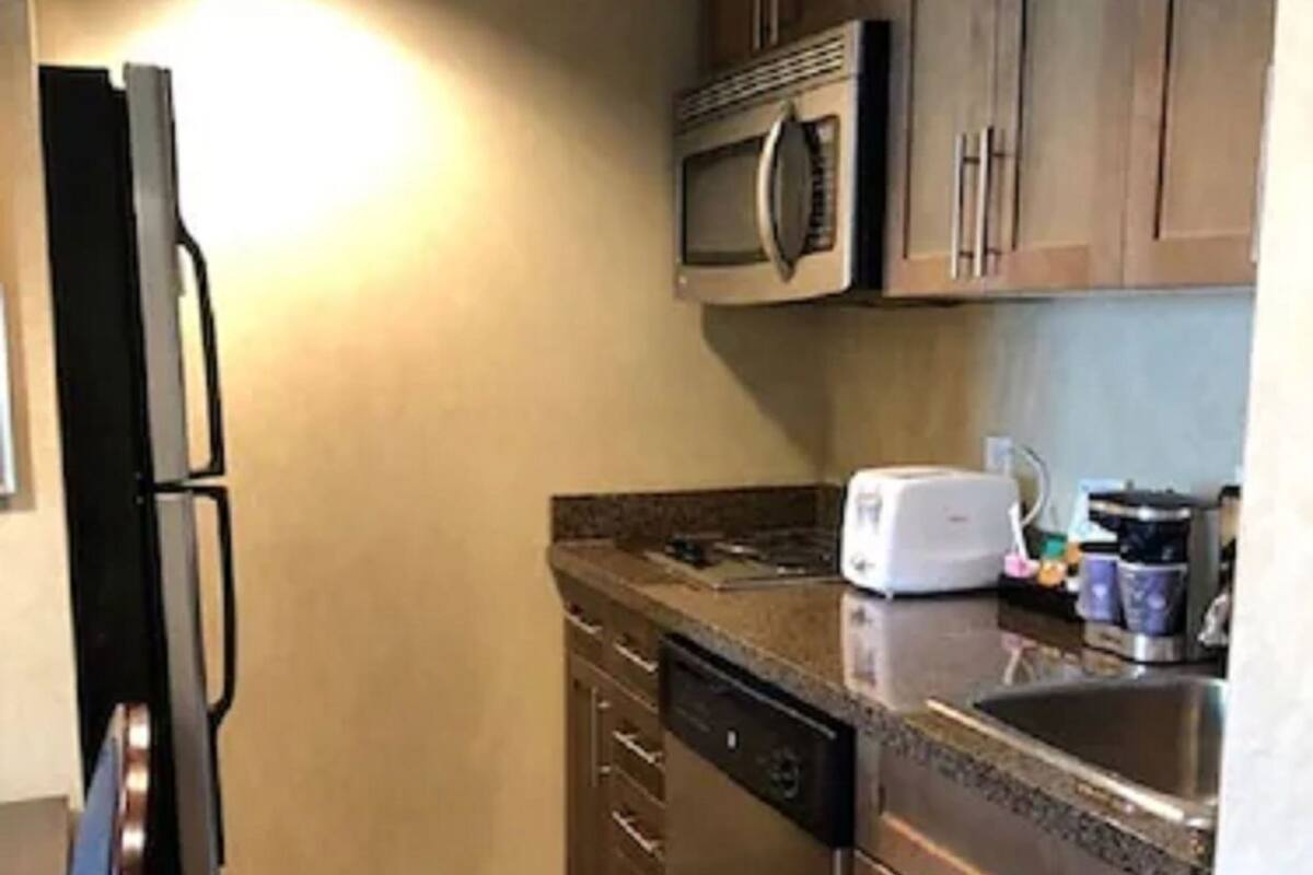 A compact kitchen with a refrigerator, microwave, dishwasher, and a sink.