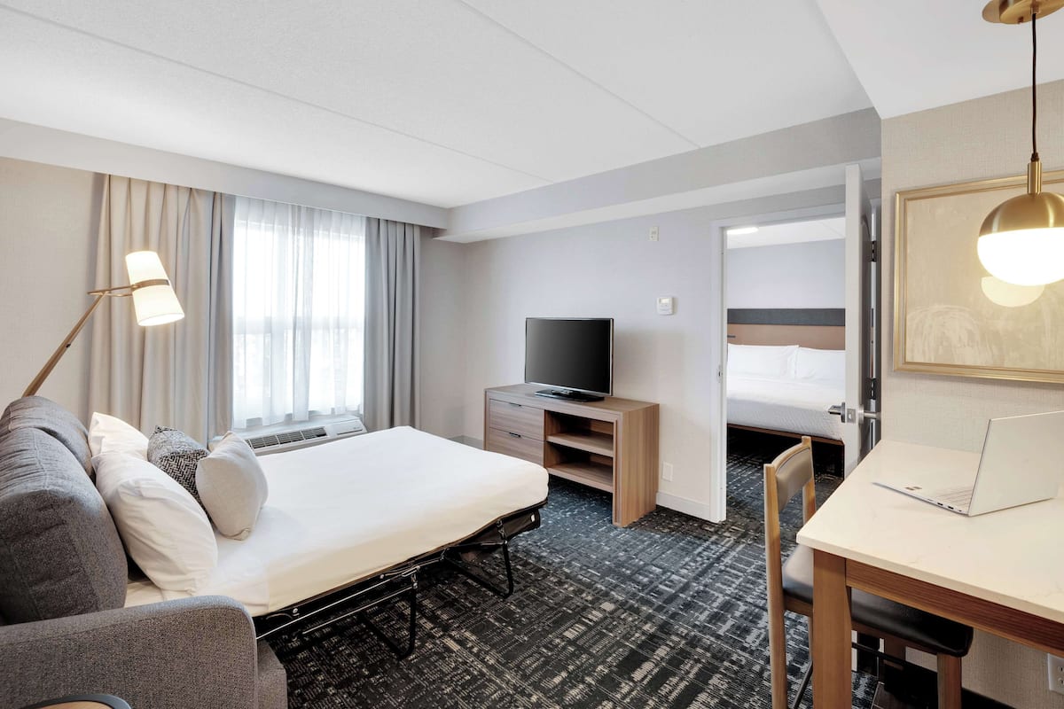 A hotel room with a bed, a desk, a television, and a chair.