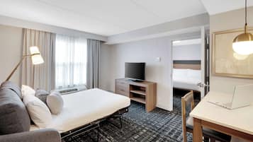Une chambre d’hôtel avec un lit, un bureau, une télévision et une chaise.