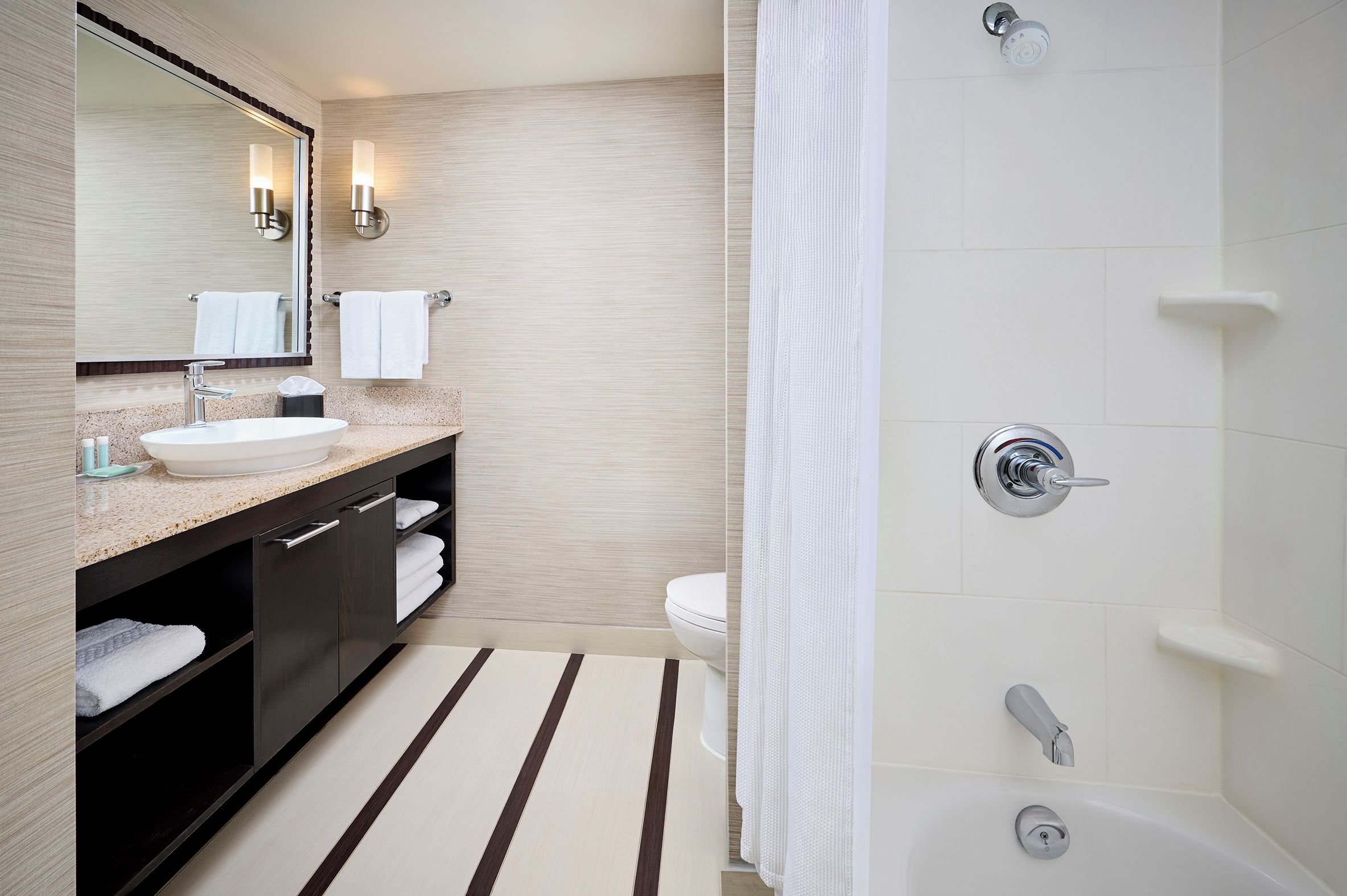 A modern bathroom with a sink, mirror, towel rack, and a shower area.