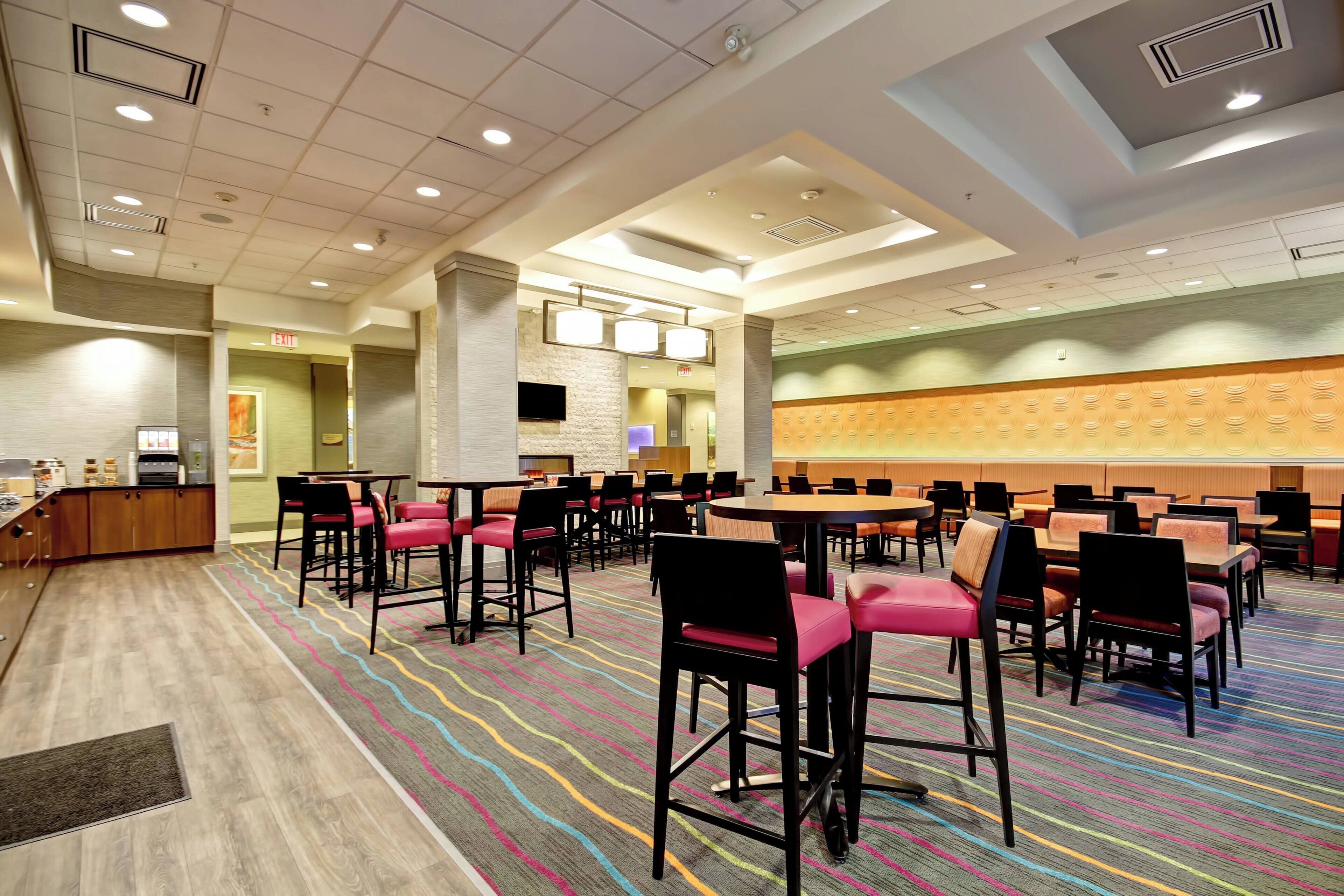 A hotel lobby with a central seating area, a reception desk, and a large wall with a patterned design.