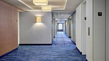 A hotel hallway with a blue carpet, light-colored walls, and a number 4 on the wall.