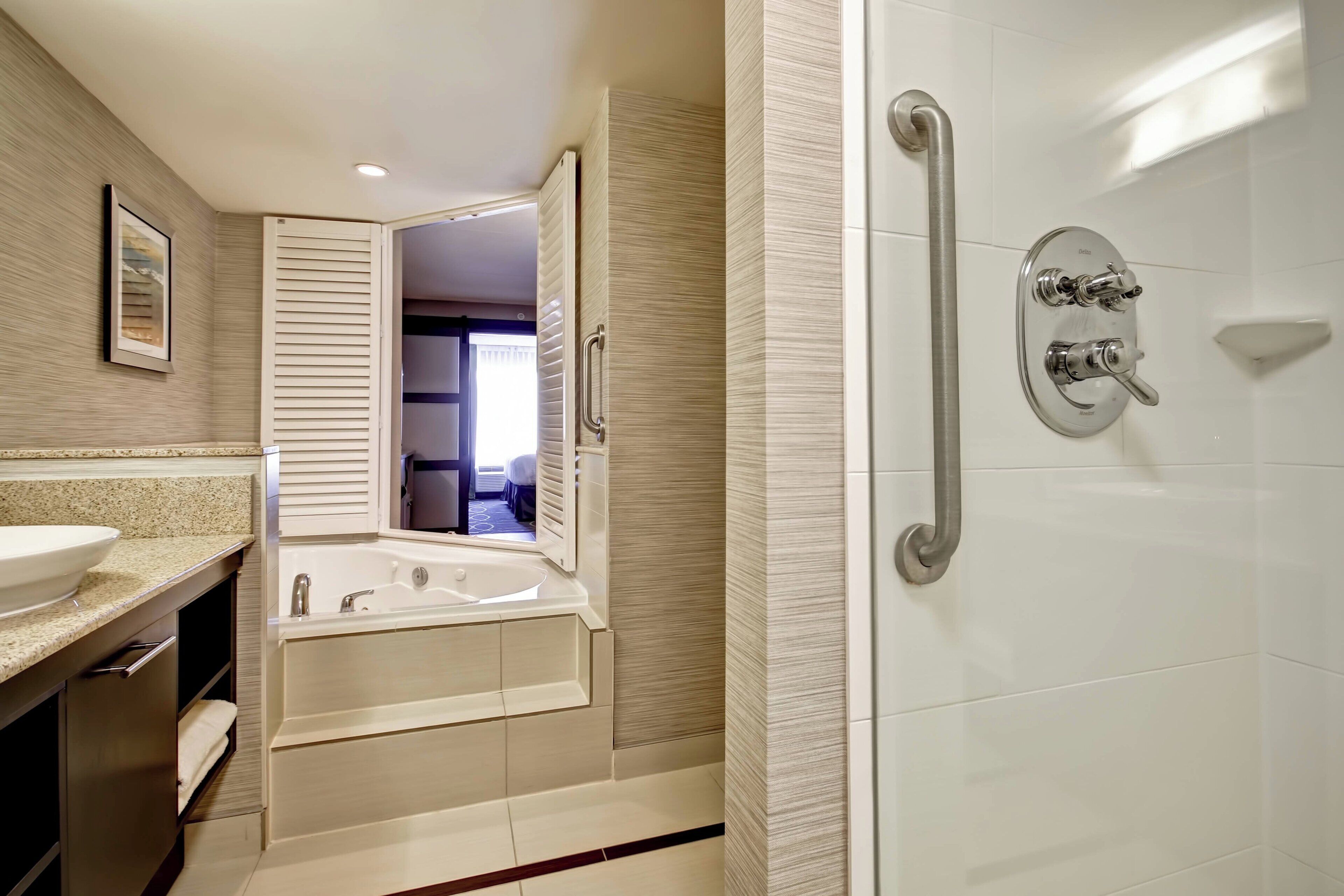 A modern bathroom with a large bathtub, a walk-in shower with a grab bar, and a sink with a countertop.