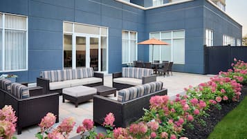 A modern outdoor patio with wicker furniture, a dining table, and a large umbrella.