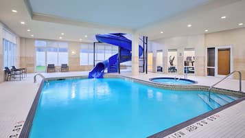 An indoor swimming pool with a blue slide, seating area, and exercise equipment.