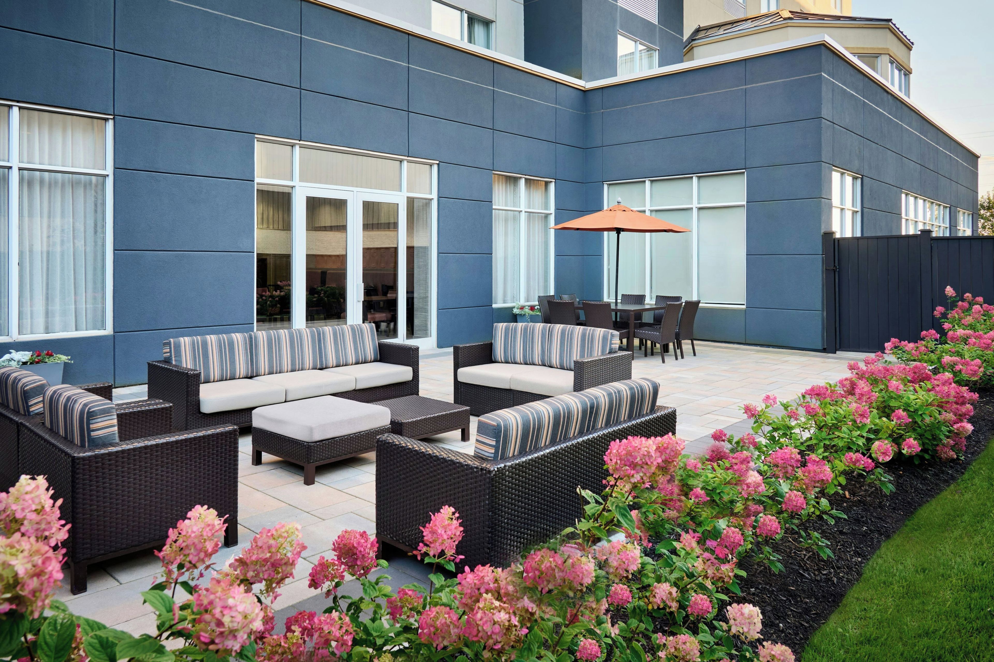 A modern outdoor patio area with wicker furniture, a dining table, and chairs.