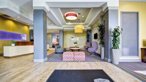 A hotel lobby with a reception desk, seating area, and a welcome mat.