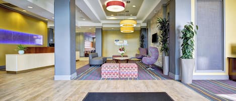 A hotel lobby with a reception desk, seating area, and a welcome mat.