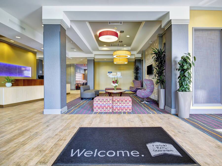 A hotel lobby with a reception desk, seating area, and a welcome mat.