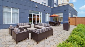 An outdoor patio area with wicker furniture, a table, and an umbrella.