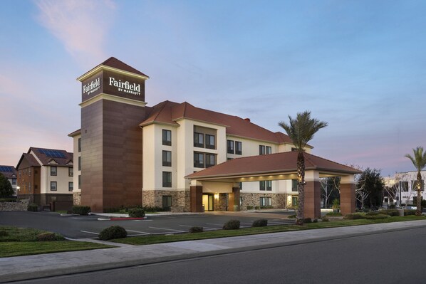 Een Fairfield by Marriott hotel met een opvallende toren, een overdekte ingang en een parkeerplaats.