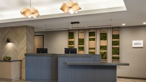 Ein Empfangsbereich mit modernem Design, mit einer Rezeption, einer Wand mit Fischgrätmuster und einem Schild mit der Aufschrift 'MARRIOTT BONVOY'.