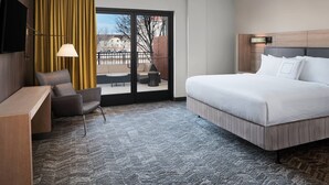 A hotel room with a large bed, a desk, a chair, a TV, and a view of the outdoors through a sliding door. - SpringHill Suites by Marriott Denver Airport (Denver)