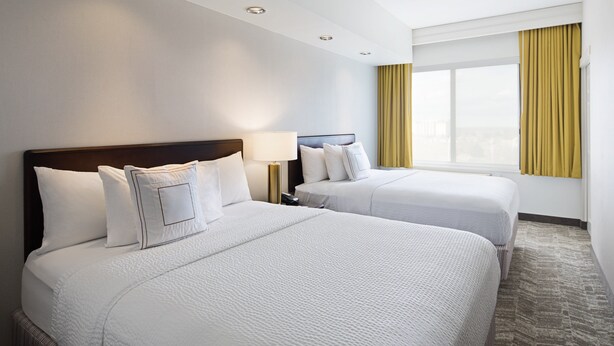 A hotel room with two beds, a window with yellow curtains, and a carpeted floor. - SpringHill Suites by Marriott Denver Airport (Denver)