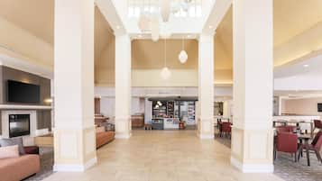 A spacious lobby with a bar area, seating, and a television.