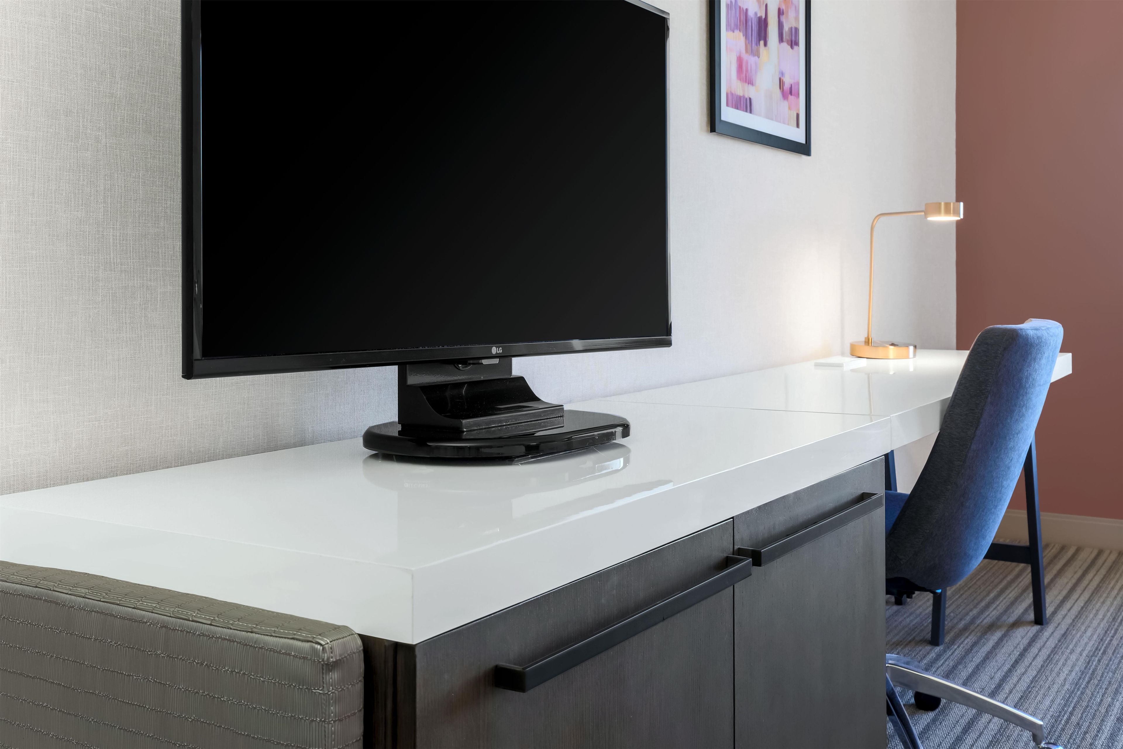 Ein modernes Hotelzimmer mit Flachbildfernseher, Schreibtisch und Stuhl.
