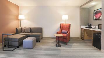 Une chambre d’hôtel équipée d’un canapé, d’un fauteuil, d’une petite table et d’une kitchenette.