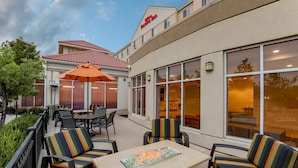 An outdoor seating area with chairs and tables, a fire feature, and a building with a sign reading "Inn of the Valley Inn". - Hilton Garden Inn Reno (Reno)