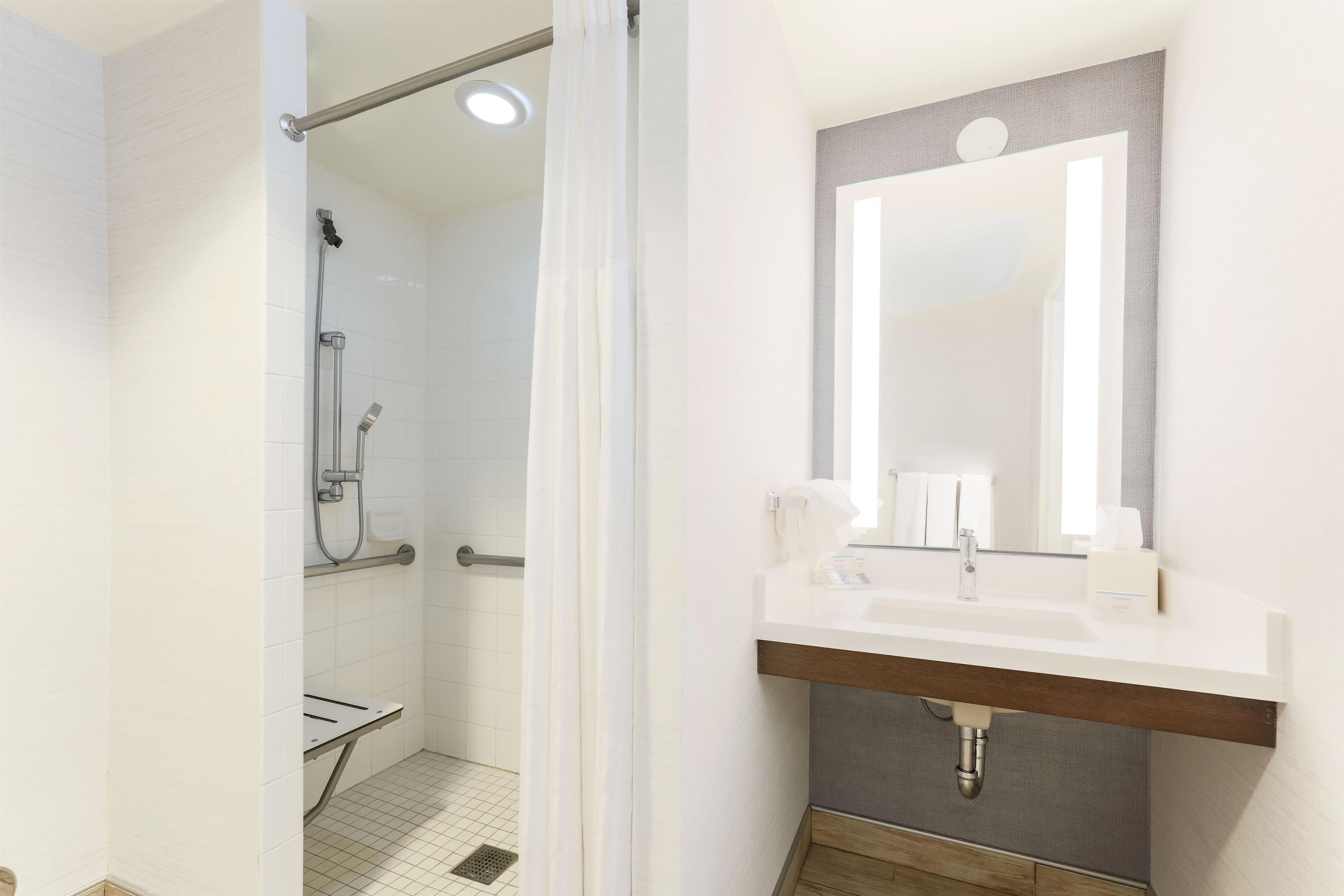 Un baño moderno con ducha, tocador con espejo y lavabo.