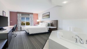A hotel room with a bed, desk, chair, and a large bathtub. - Hilton Garden Inn Reno (Reno)