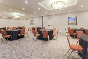 A conference room with round tables and orange chairs, carpeted floor, recessed ceiling lights, and a framed landscape painting. - Hilton Garden Inn Reno (Reno)