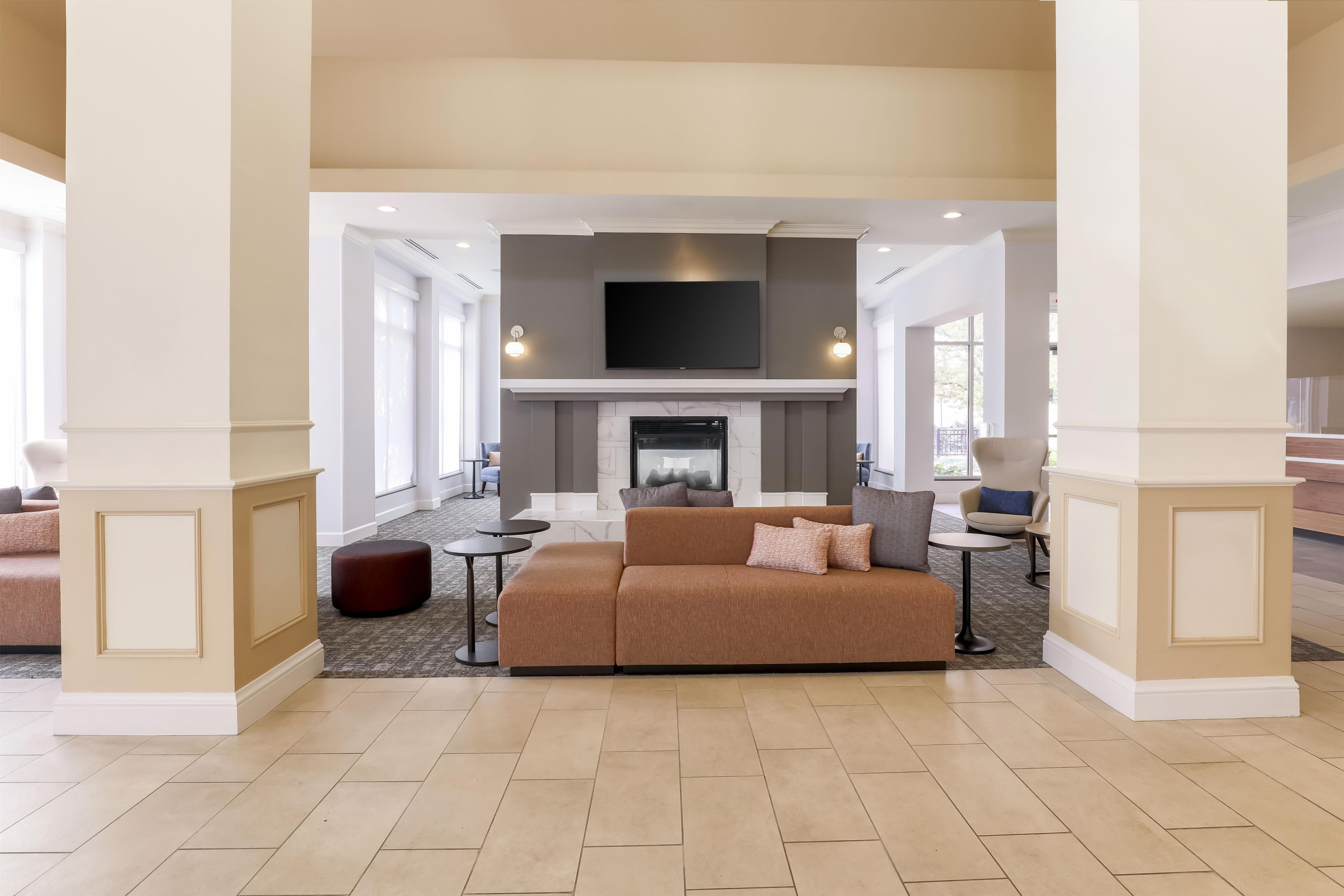 A spacious living area with a fireplace, comfortable seating, and a flat-screen TV mounted above.