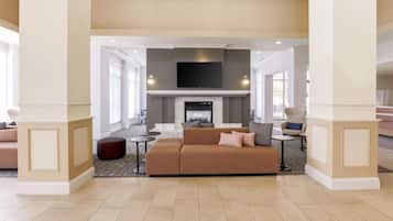 A spacious living area with a fireplace, comfortable seating, and a flat-screen TV mounted above.