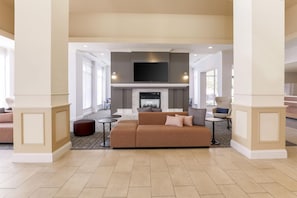 A spacious living area with a fireplace, comfortable seating, and a flat-screen TV mounted above.