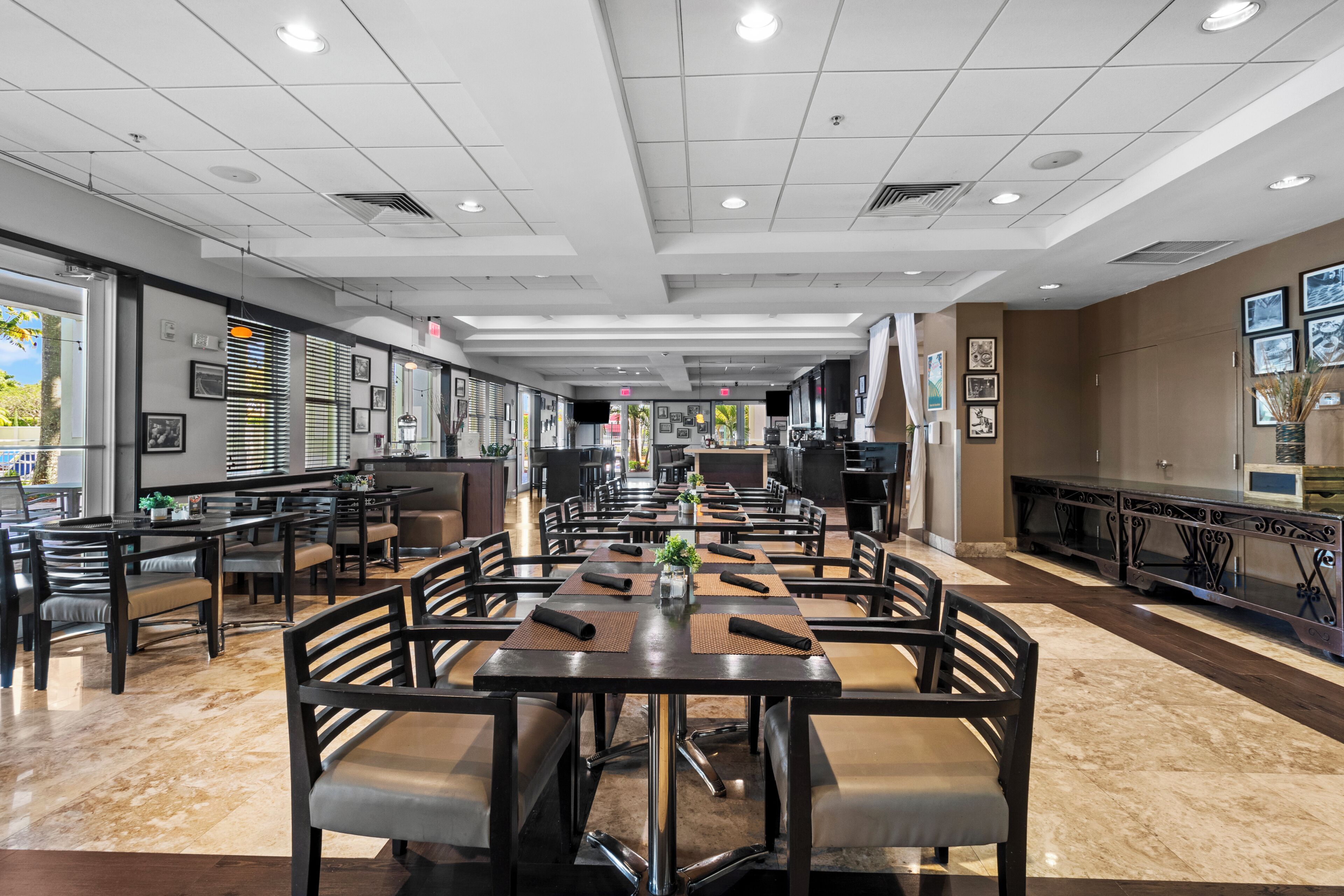 A spacious indoor dining area with multiple tables and chairs, a long counter, and a view of the outdoors through large windows.