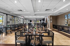 Un vaste espace de restauration intérieur, doté de nombreuses tables et chaises, d’un long comptoir et offrant une vue sur l’extérieur grâce à de grandes fenêtres.