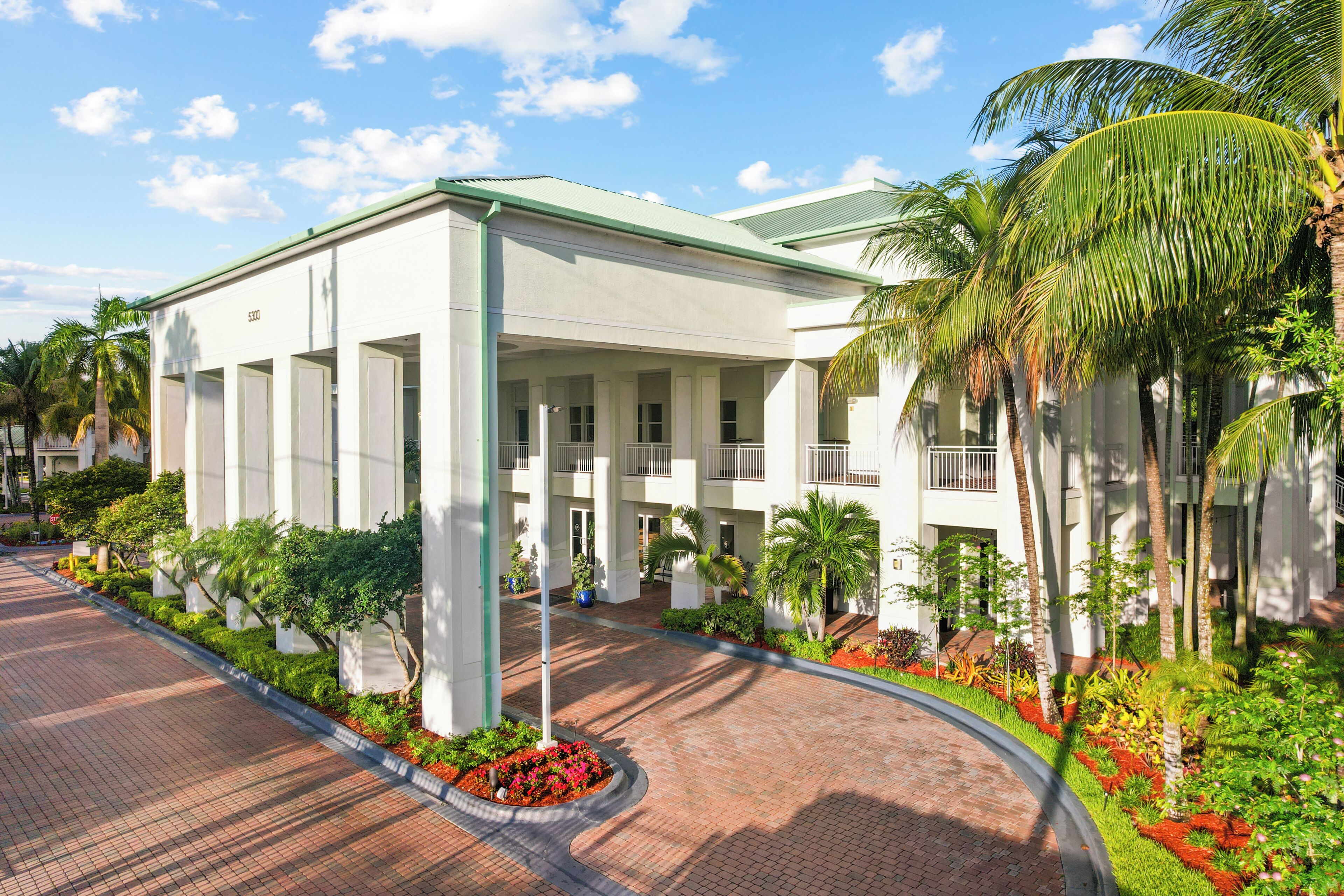 A white building with a green roof, columns, and a covered entrance.