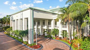 A white building with a green roof, columns, and a covered entrance.