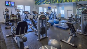 Un gimnasio con cintas de correr, máquinas de pesas y pelotas de ejercicio.