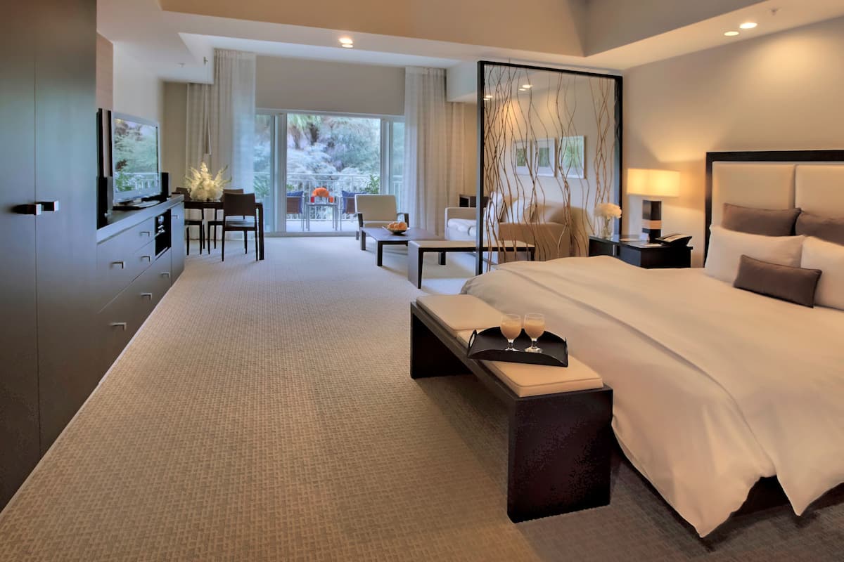 Une chambre d’hôtel moderne, dotée d’un grand lit, d’un bureau, d’une chaise et offrant une vue sur l’extérieur.