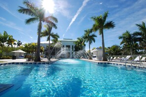 A swimming pool with a water fountain, surrounded by palm trees and lounge chairs. - Provident Doral at the Blue Miami (Miami)