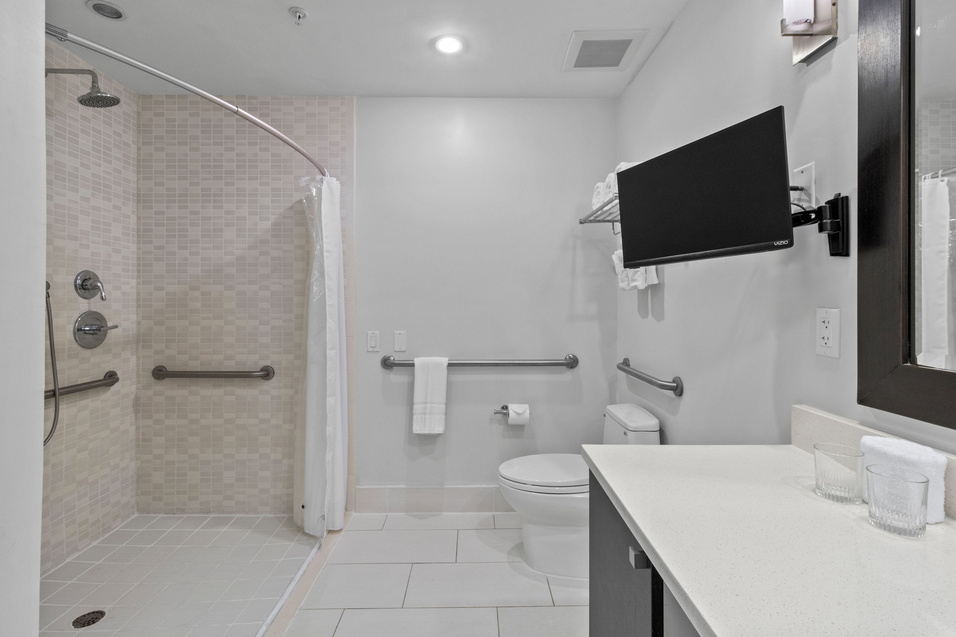 A modern bathroom with a shower, toilet, and a mounted TV.