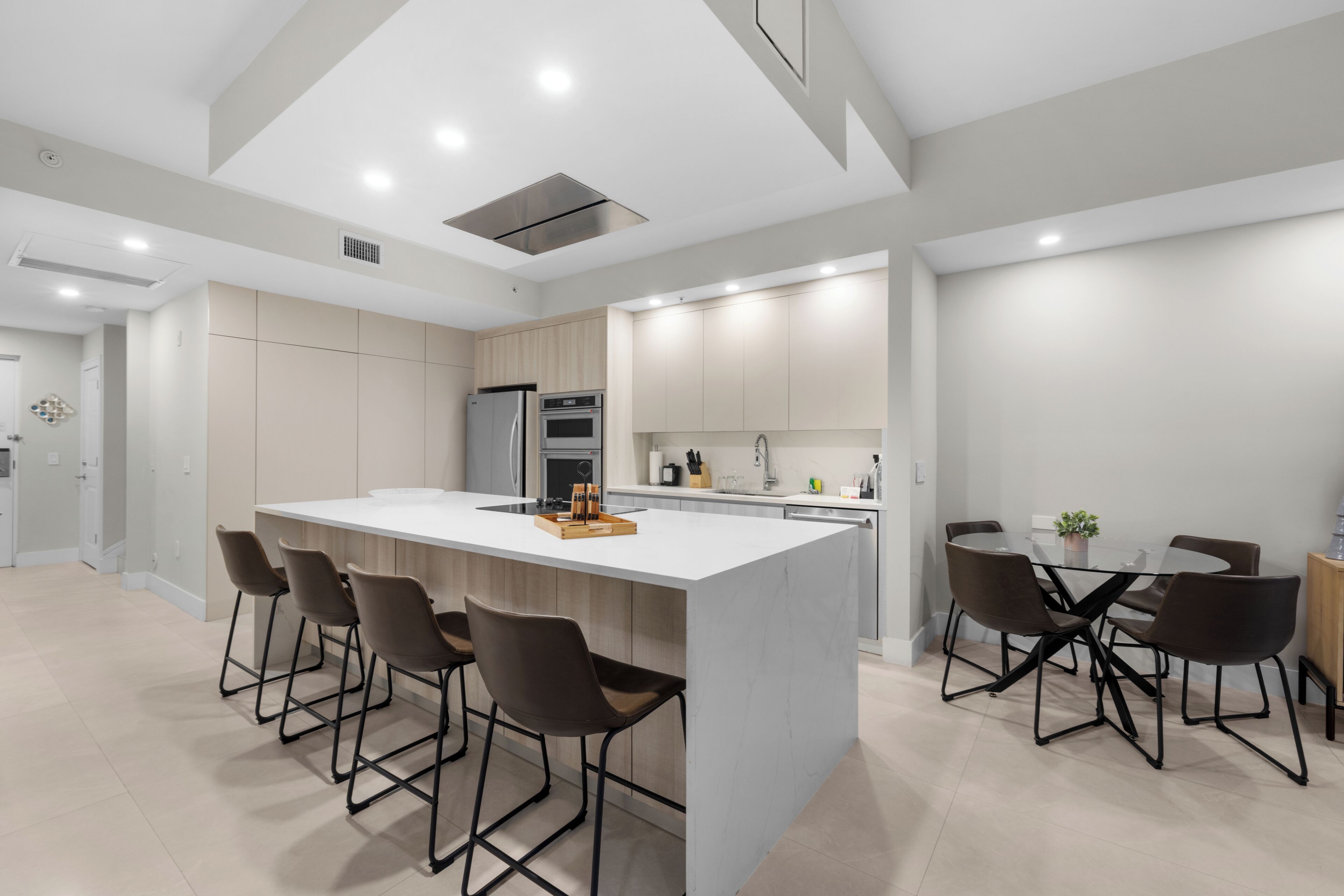 Une cuisine moderne dotée d’un îlot central, de tabourets de bar et d’une table à manger avec des chaises.