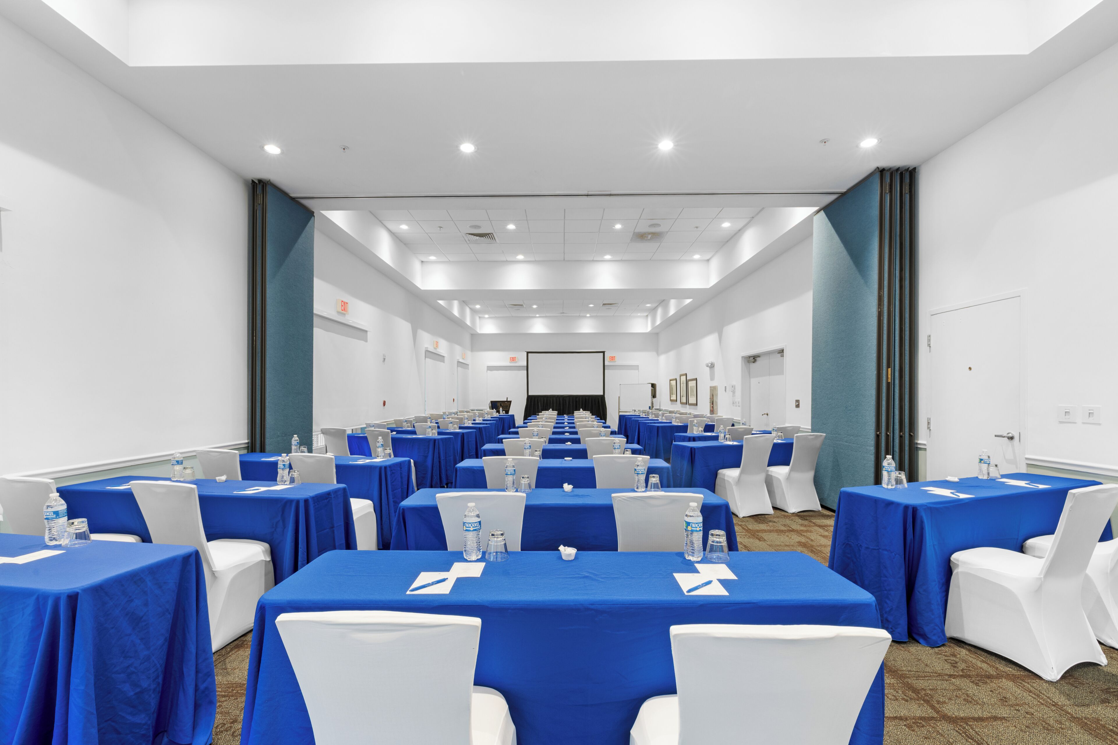 A conference room with rows of tables, chairs, and water bottles.