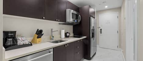 A modern kitchen with dark cabinets, stainless steel appliances, and a white countertop.