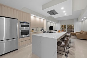 A modern kitchen with a central island, stainless steel appliances, and a dining area with bar stools.