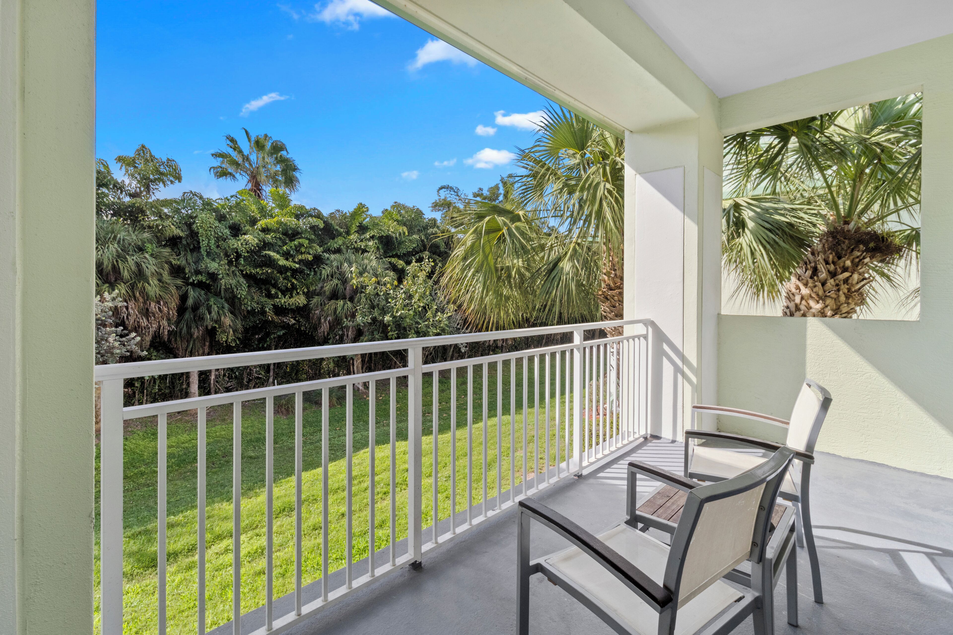 Un balcone con vista su un rigoglioso giardino e palme.