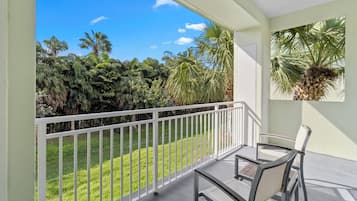 A balcony with a view of a lush garden and palm trees.